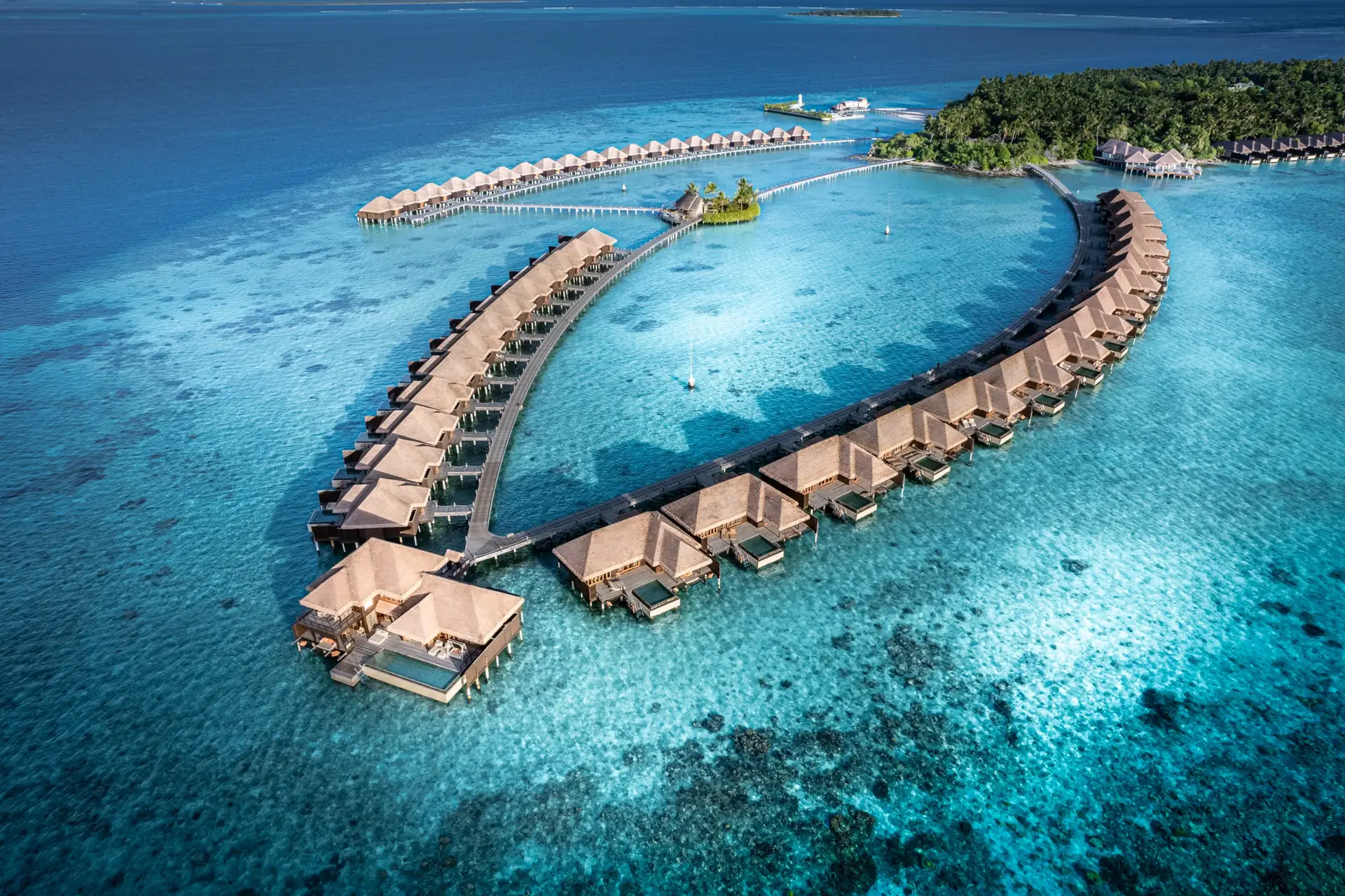 Aerial view of overwater villas over a turquoise lagoon